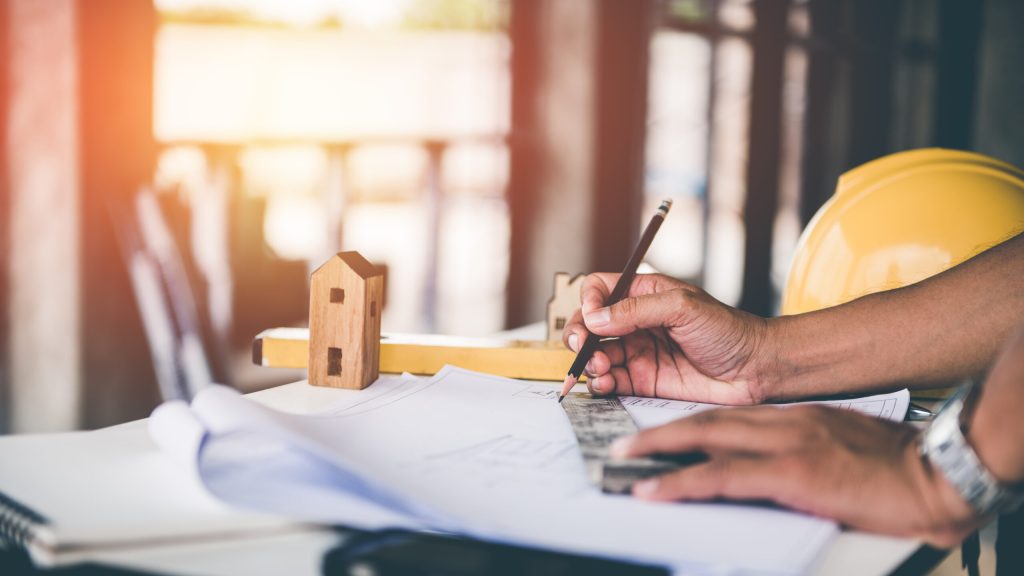 architect man working with blueprints,engineer inspection in workplace for architectural plan,sketching a construction project ,selective focus.